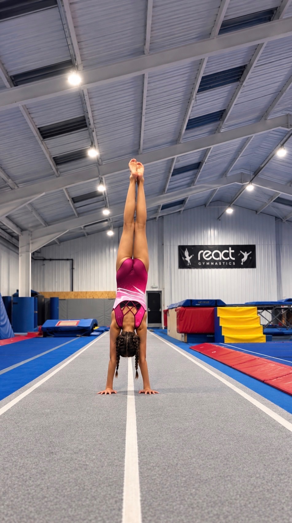 Gymnast holding a handstand walk along the 25m tumble track at React TGC